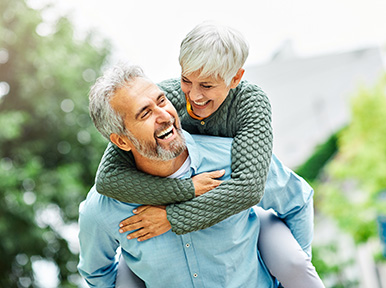 Older couple laughing outdoors, representing lasting healthy smiles and quality dental care for seniors